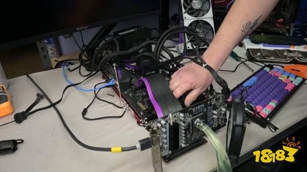A person is assembling a custom PC with Corsair Vengeance RAM and visible EKWB cooling components on a test bench, next to a colorful mechanical keyboard.