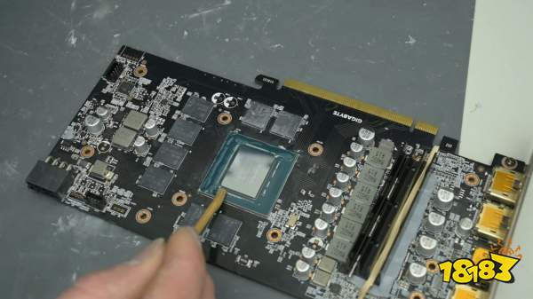 A Gigabyte NVIDIA GeForce graphics card with its GPU exposed and a tool applying thermal paste.