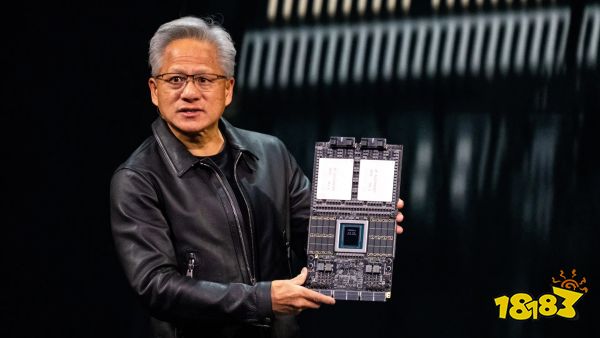 A presenter in a black leather jacket holds a large computing board with visible components and circuitry.