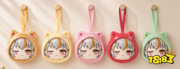 Five plush keychains with winking cartoon faces and animal ear hoods in yellow, orange, pink, red, and green hang in a row.