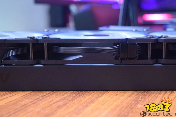 A close-up of a black unbranded graphics card with visible power cables and cooling fans resting on a wooden surface.